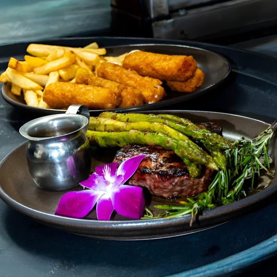Black Bull Steakhouse's grilled steak with asparagus, rosemary, sauce, and a purple orchid, with fries and mozzarella sticks.